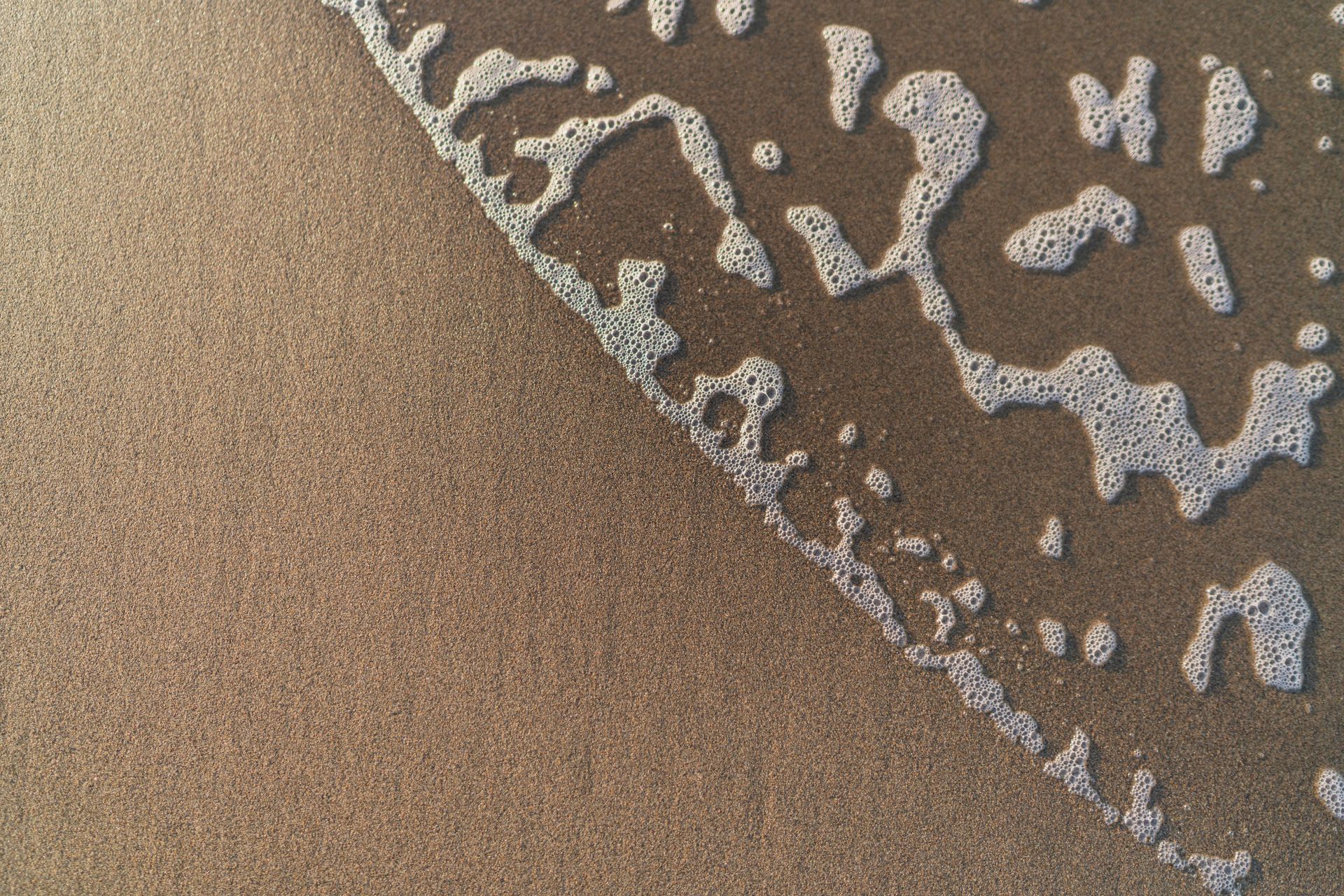 Sandy beach with foamy ocean water washing ashore. Sandy beach with foamy ocean water washing ashore.