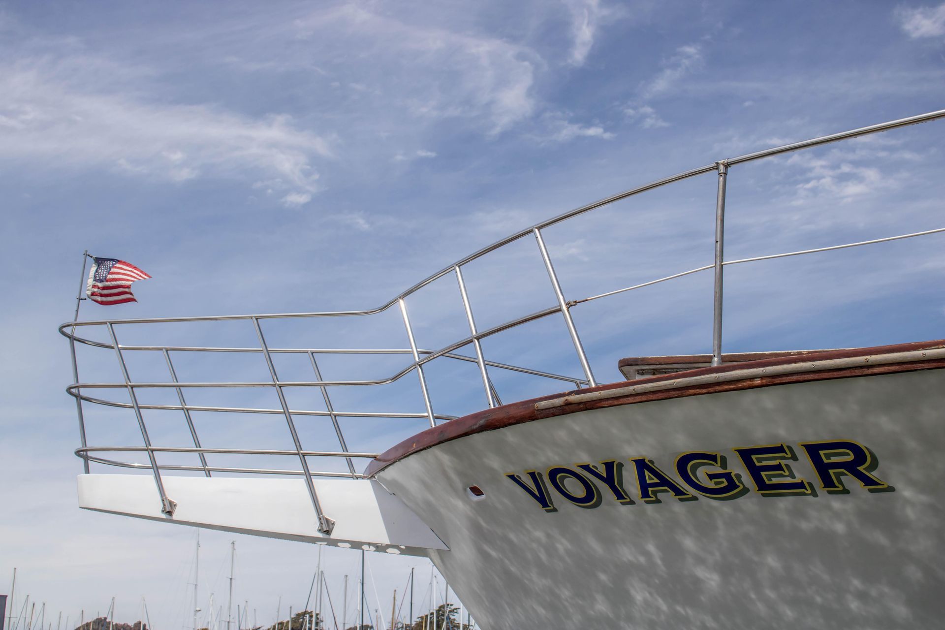 Two white canvas director chairs face a round table set with fruit, champagne, and glasses on a yacht deck.