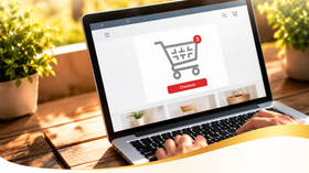 Laptop screen with shopping cart icon and red buy button on a desk in warm sunlight