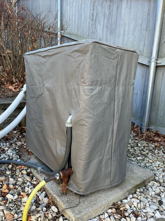 A hose is attached to a heater with a cover on it.