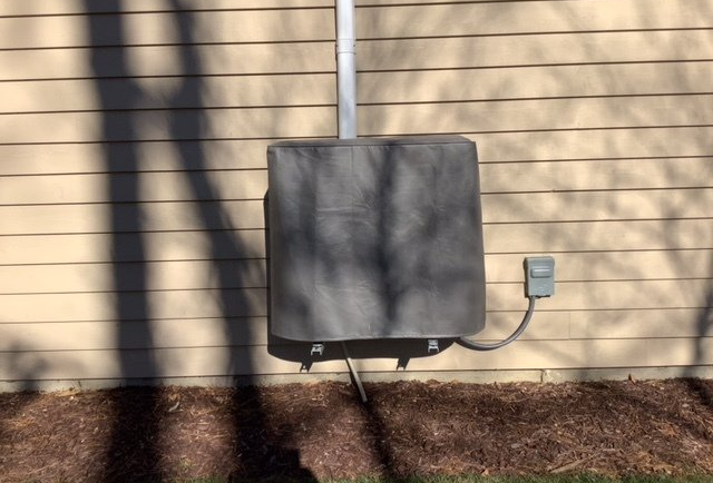 A box with a cover on it is attached to the side of a house.