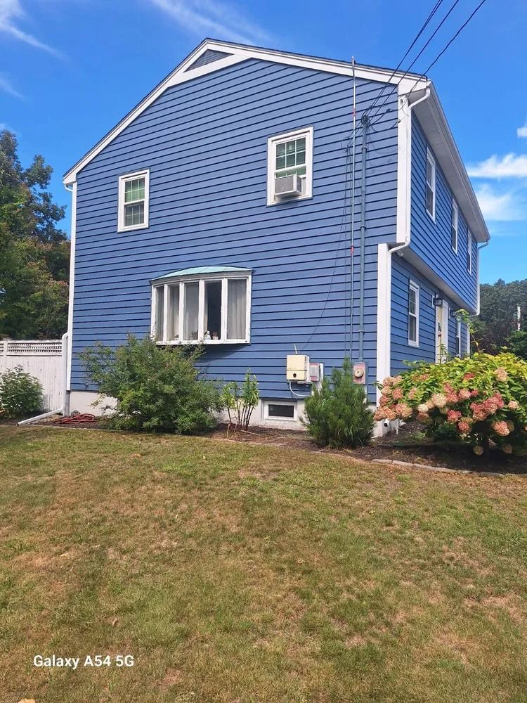 Blue two-story house with white trim and a sloped lawn, viewed from the front yard