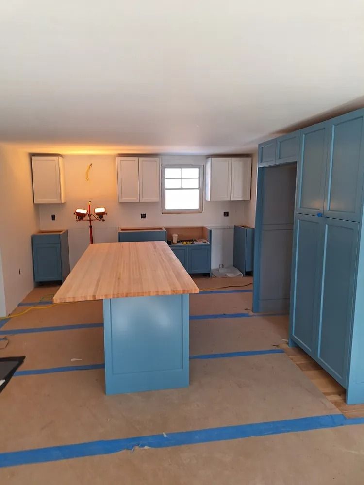 Unfinished kitchen with blue cabinets, central island, and taped floor layout under renovation