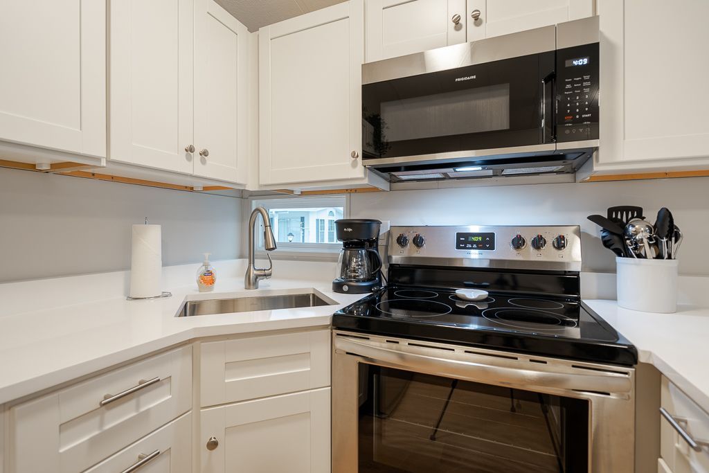 A clean kitchen with white cabinets, light countertops, a stainless steel stove, and an over-the-range microwave.