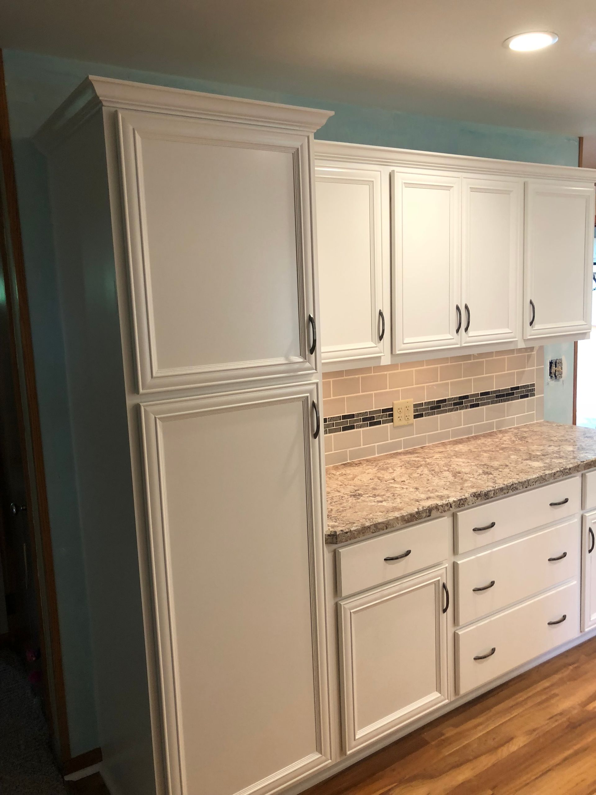 White kitchen cabinets with granite countertops and a tiled backsplash in a residential kitchen.