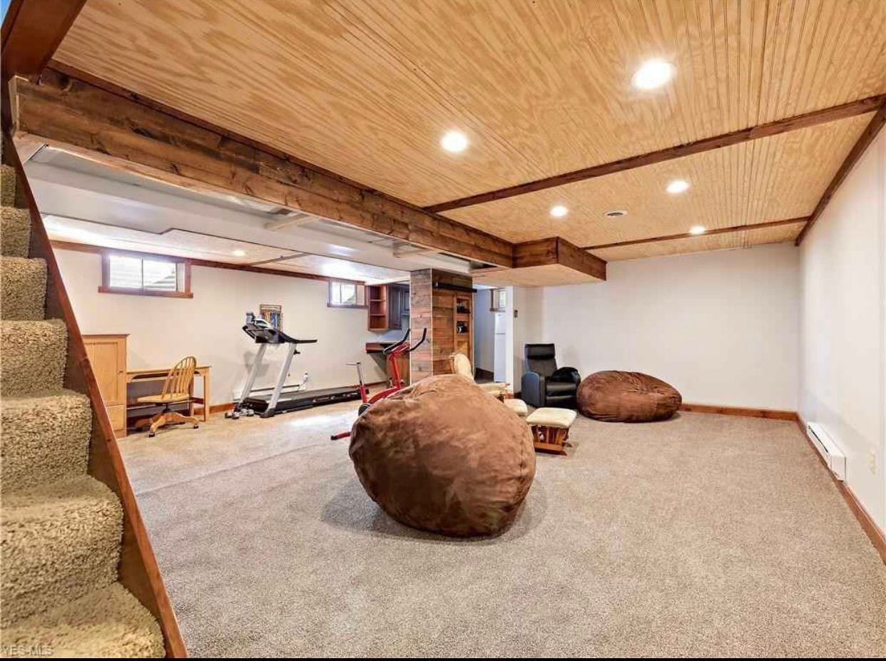 A finished basement with carpet, a wood-paneled ceiling, two brown beanbag chairs, and an exercise treadmill.