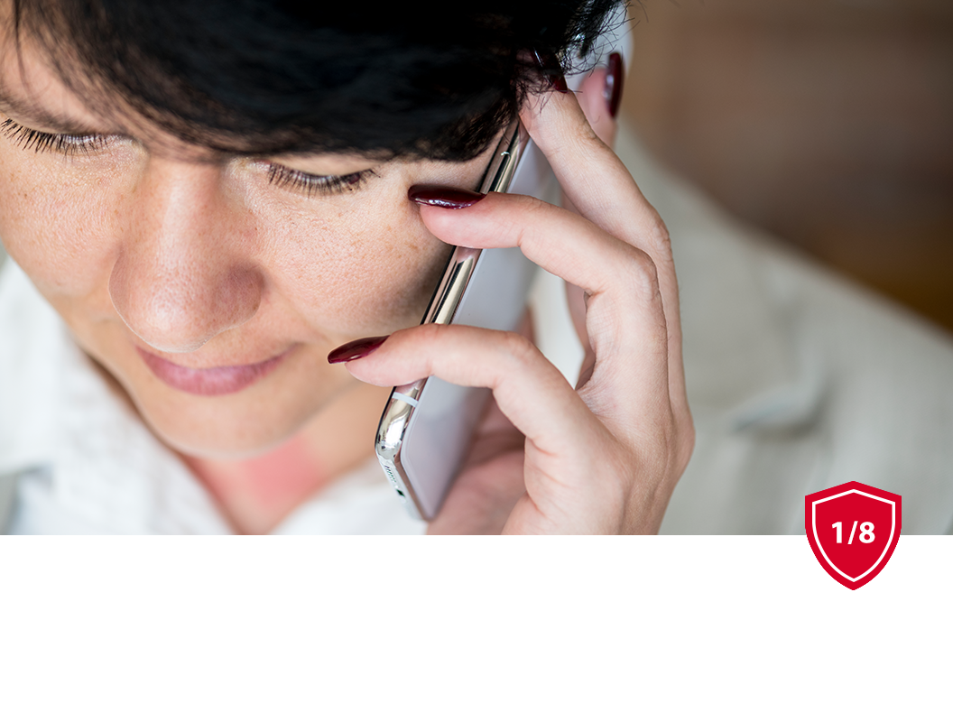 A person holding a white smartphone to their ear while focused on the device.