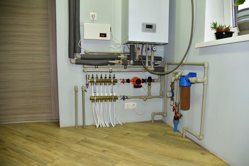 Heating System With Pipes, Boiler, and Water Filter in a Light-coloured Room — Ian Stanley Plumbing In Avoca, QLD
