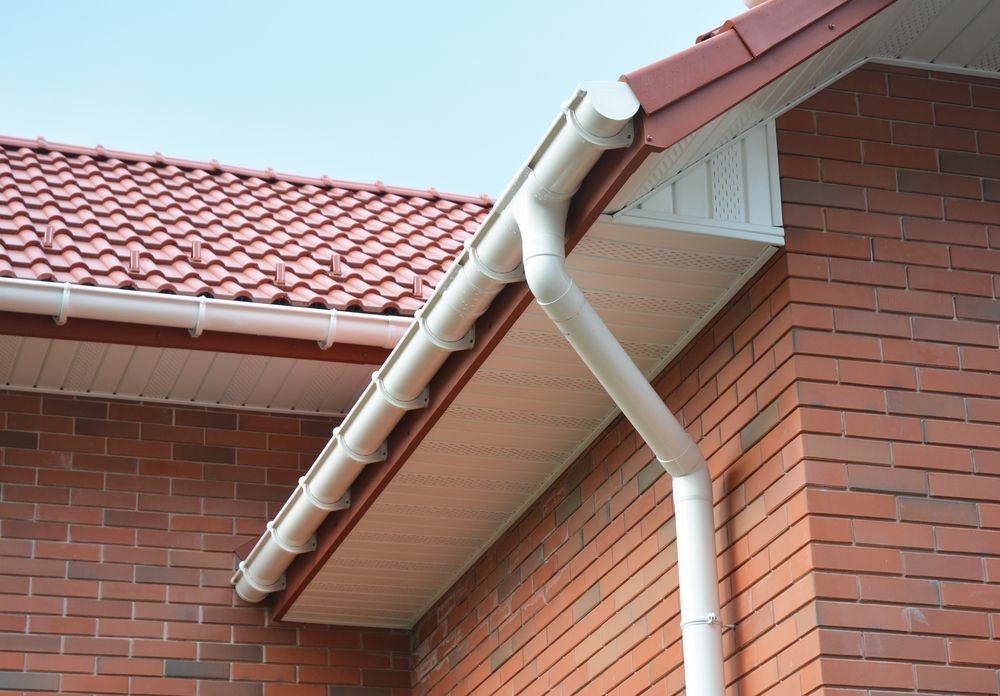 White Rain Gutter System on a Brick House With a Red Tiled Roof — Ian Stanley Plumbing In Avoca, QLD