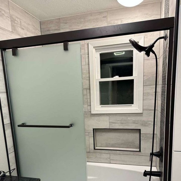 A bathroom with a sliding glass shower door and a tub.