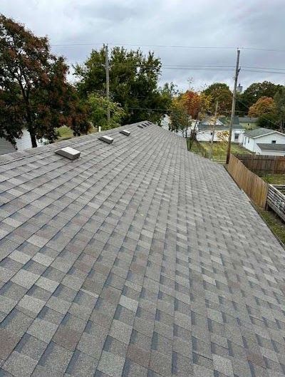 A roof with a lot of shingles on it and trees in the background.