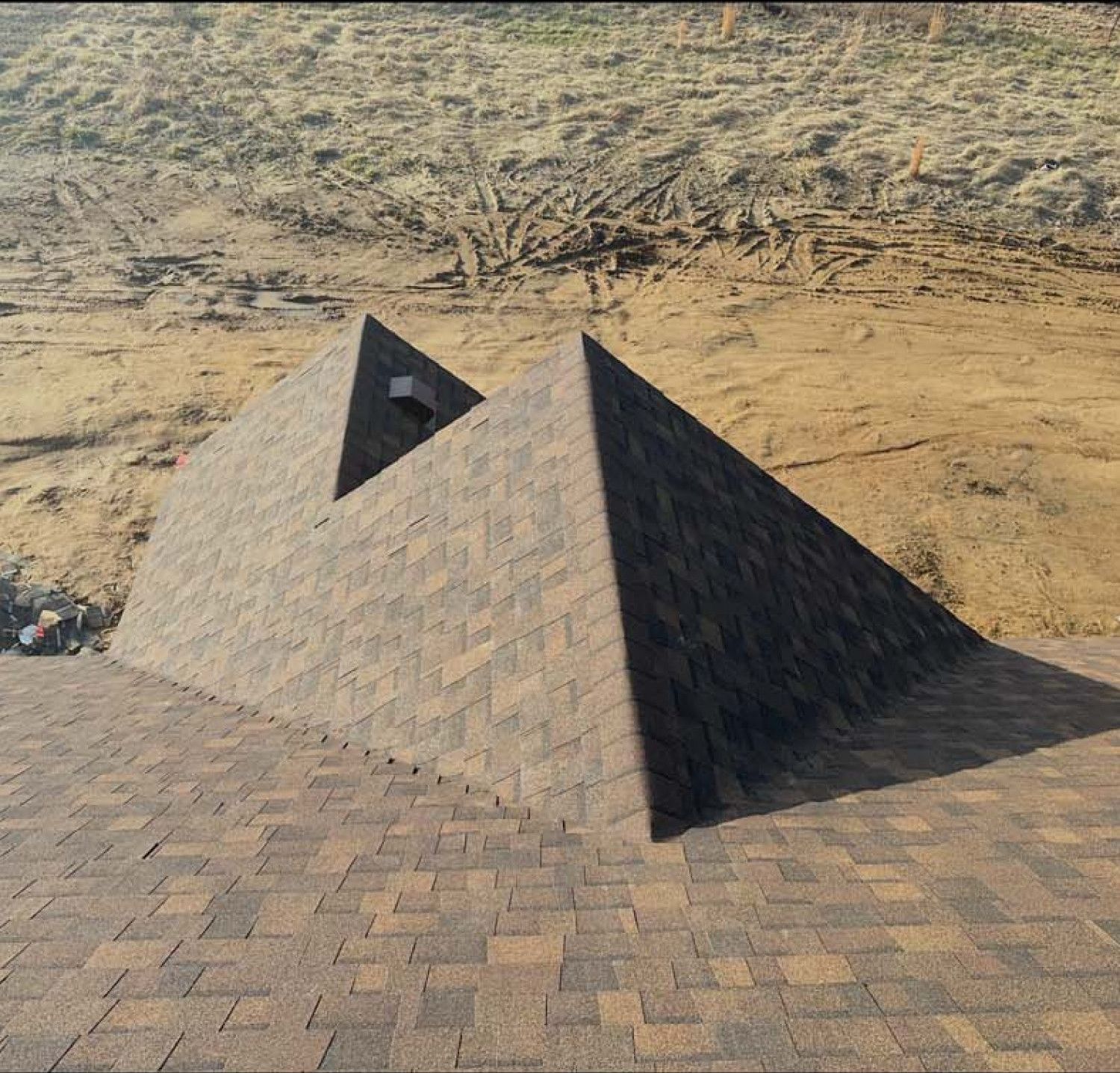 A pyramid made of shingles is sitting on top of a brick roof.
