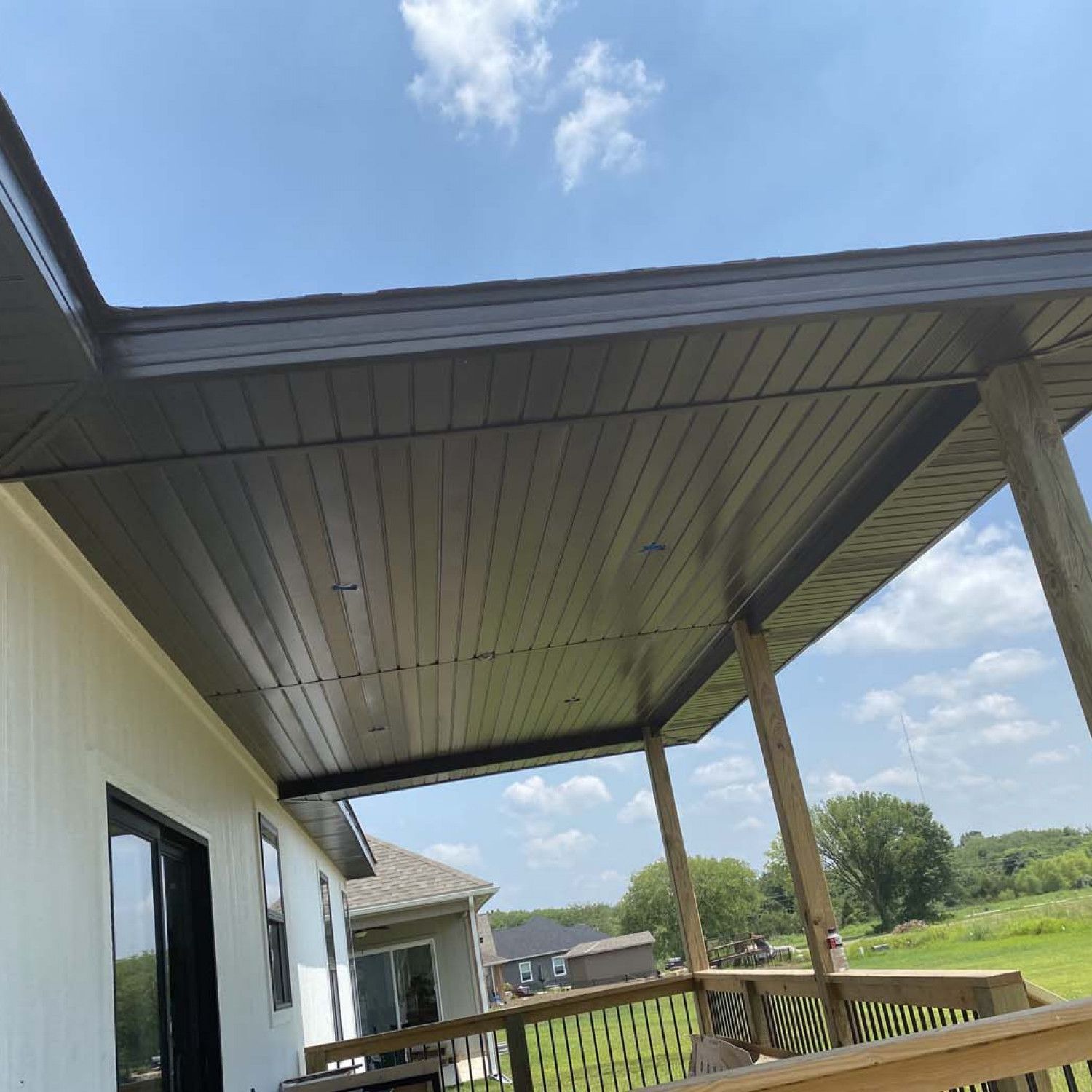 The roof of a house with a porch and a blue sky in the background.