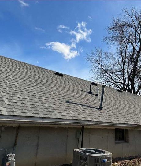 A house with a roof that has shingles on it and a tree in the background.