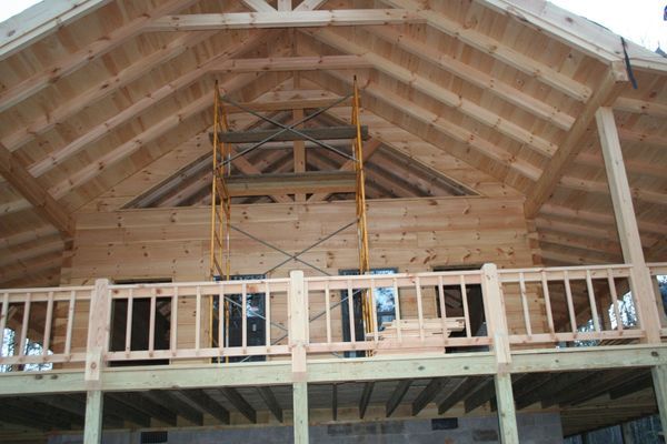 Wooden building under construction with scaffolding on a wooden deck.
