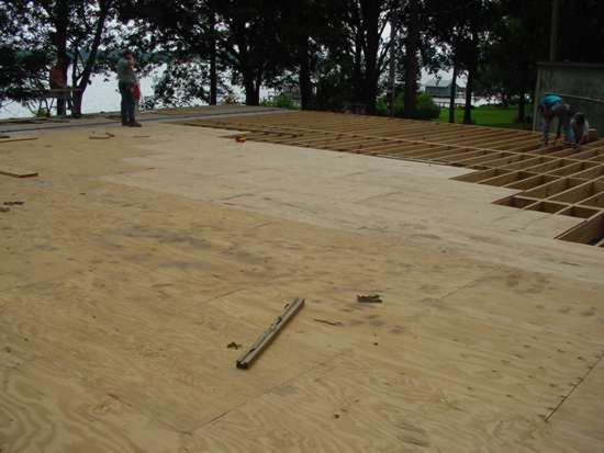 Plywood flooring being installed on wooden framework.