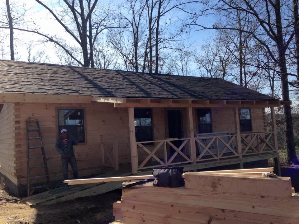 Cabin under construction with a porch and ramp.