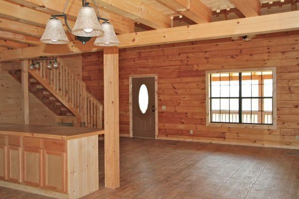 Interior of a wood-paneled room with a staircase, bar, door, and window. Overhead lighting.