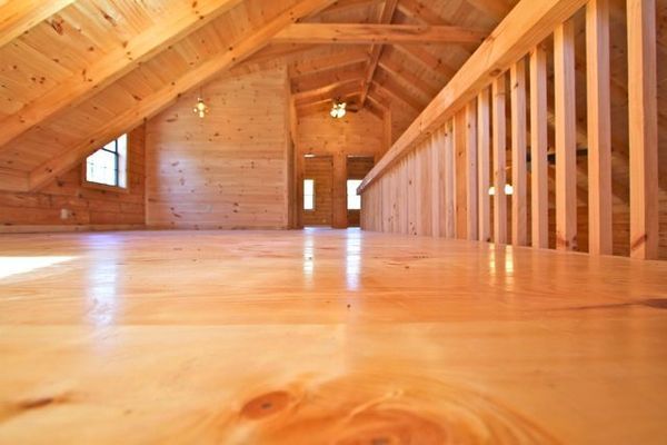 Wooden loft interior with glossy floor and railing.