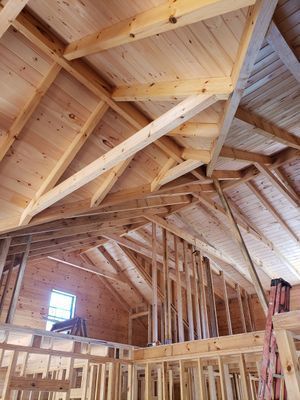 Interior view of a wooden roof under construction with rafters and supporting beams.