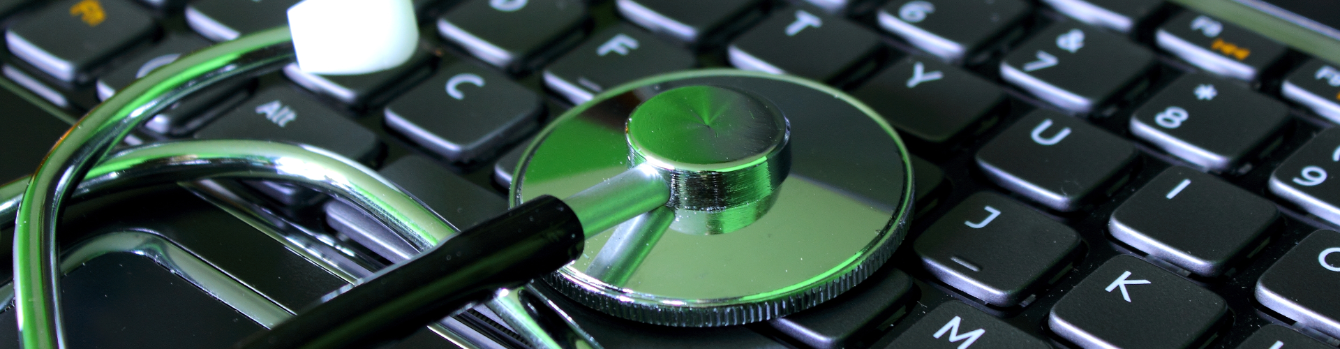 A stethoscope is sitting on top of a laptop keyboard.