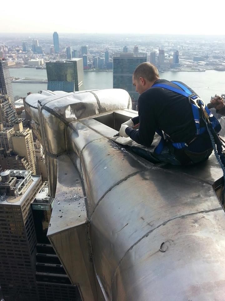 A man sitting on top of a building with a city in the background