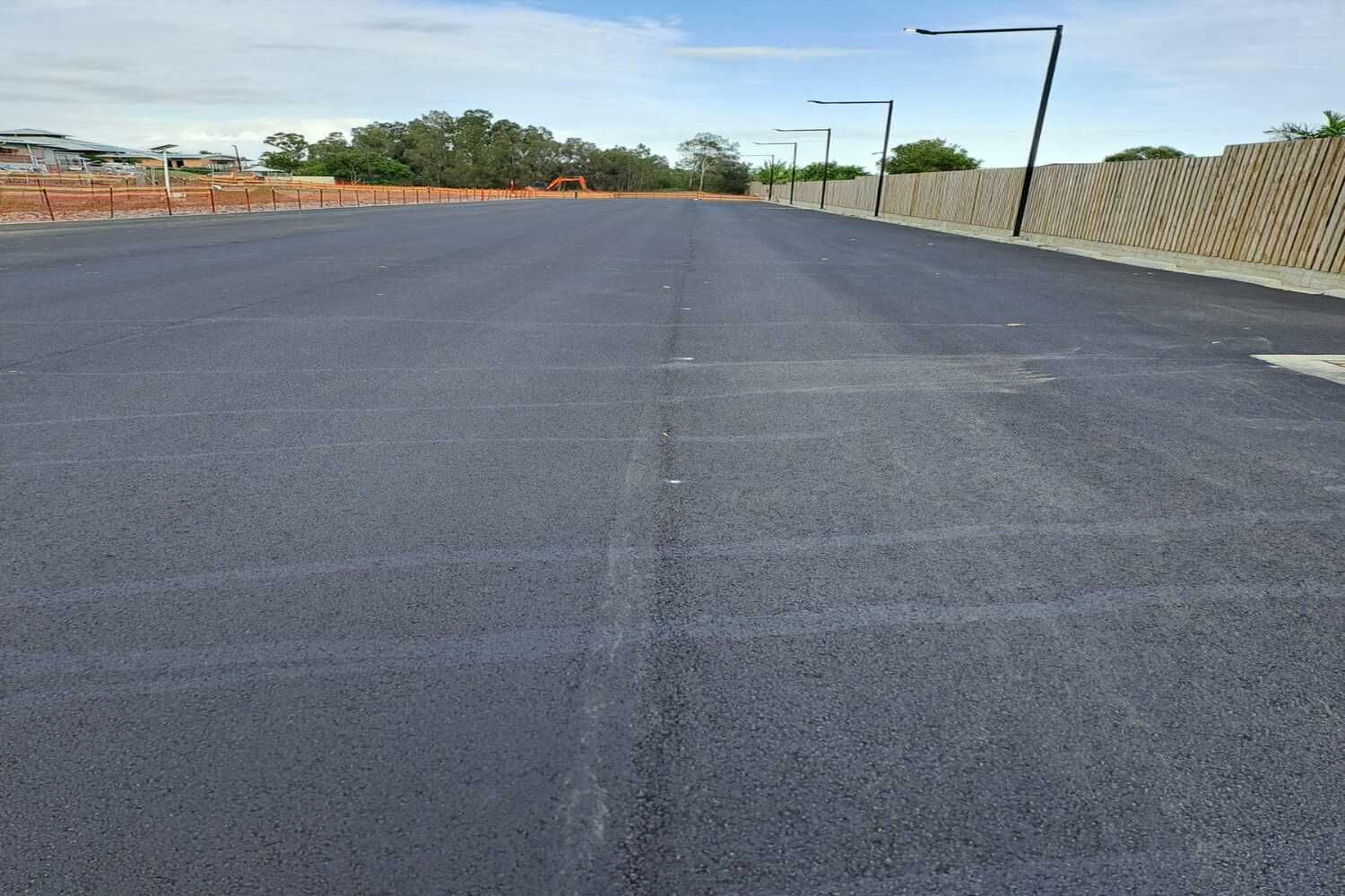 A Black Asphalt Road With A Fence In The Background — Spraywayz Linemarking Pty Ltd In Booral, QLD
