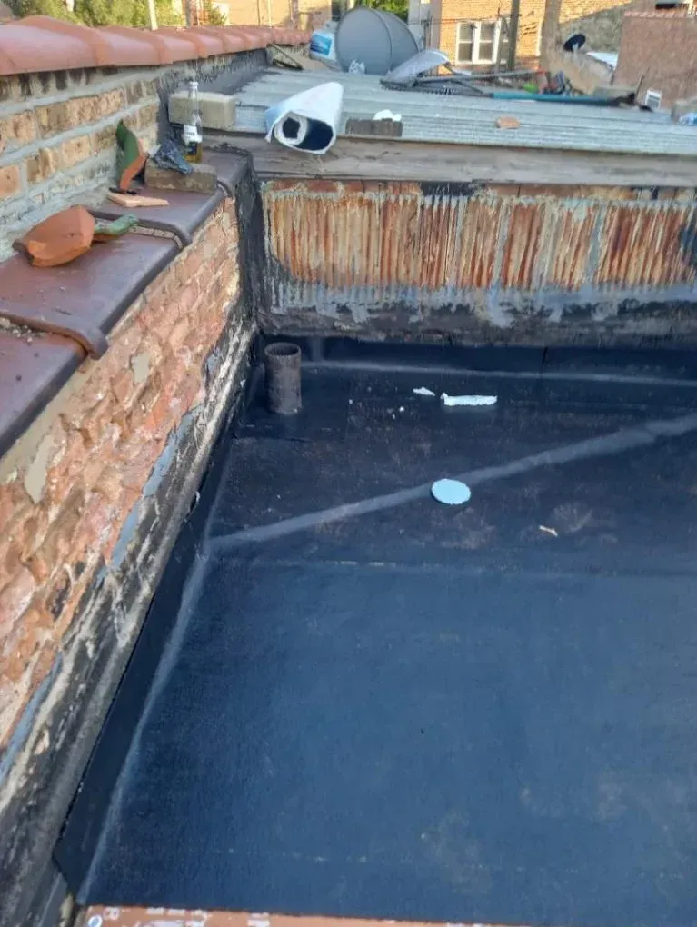 Rooftop pool under repair with dark liner, brick walls, and rusted edge trim