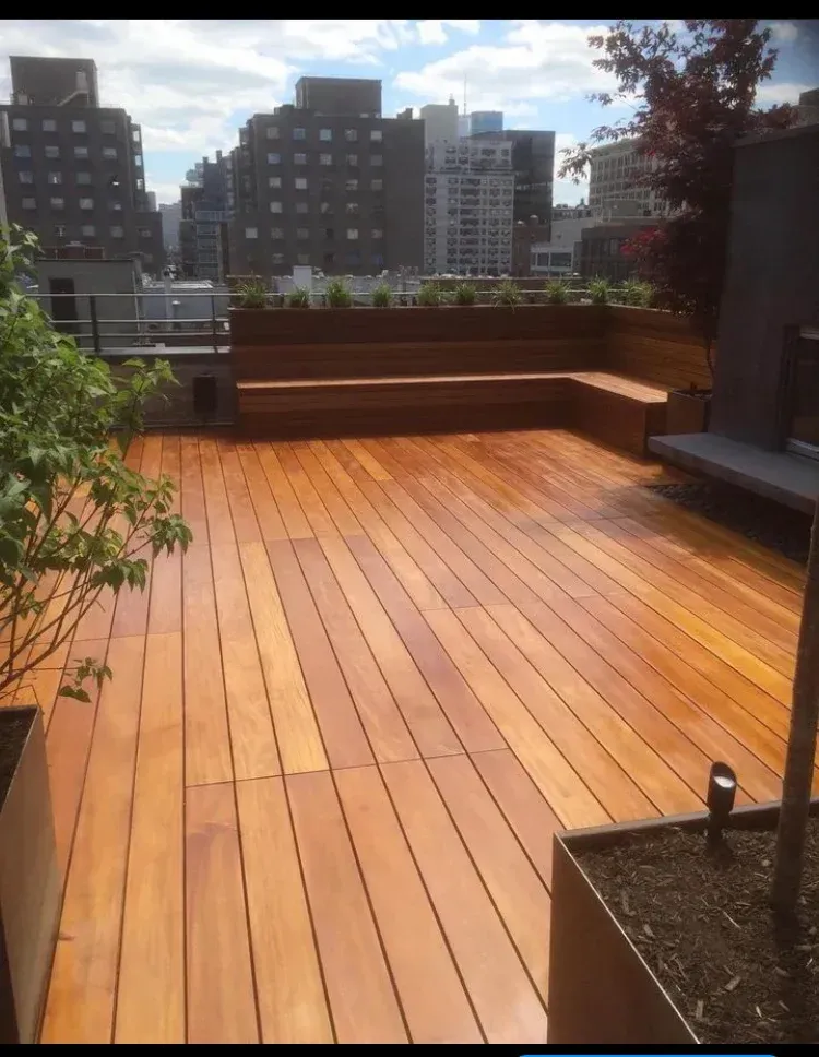 Rooftop wooden deck with built-in benches and city buildings in the background.