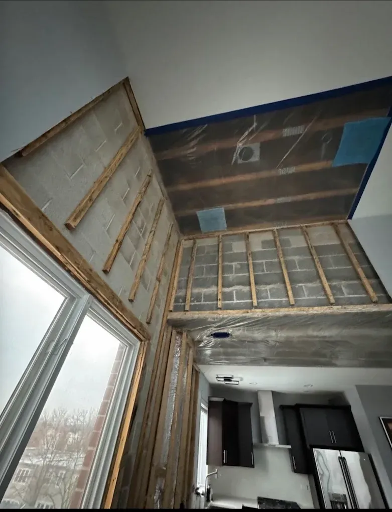 Modern room interior with tall windows, exposed wood beams, and a slanted skylight ceiling.