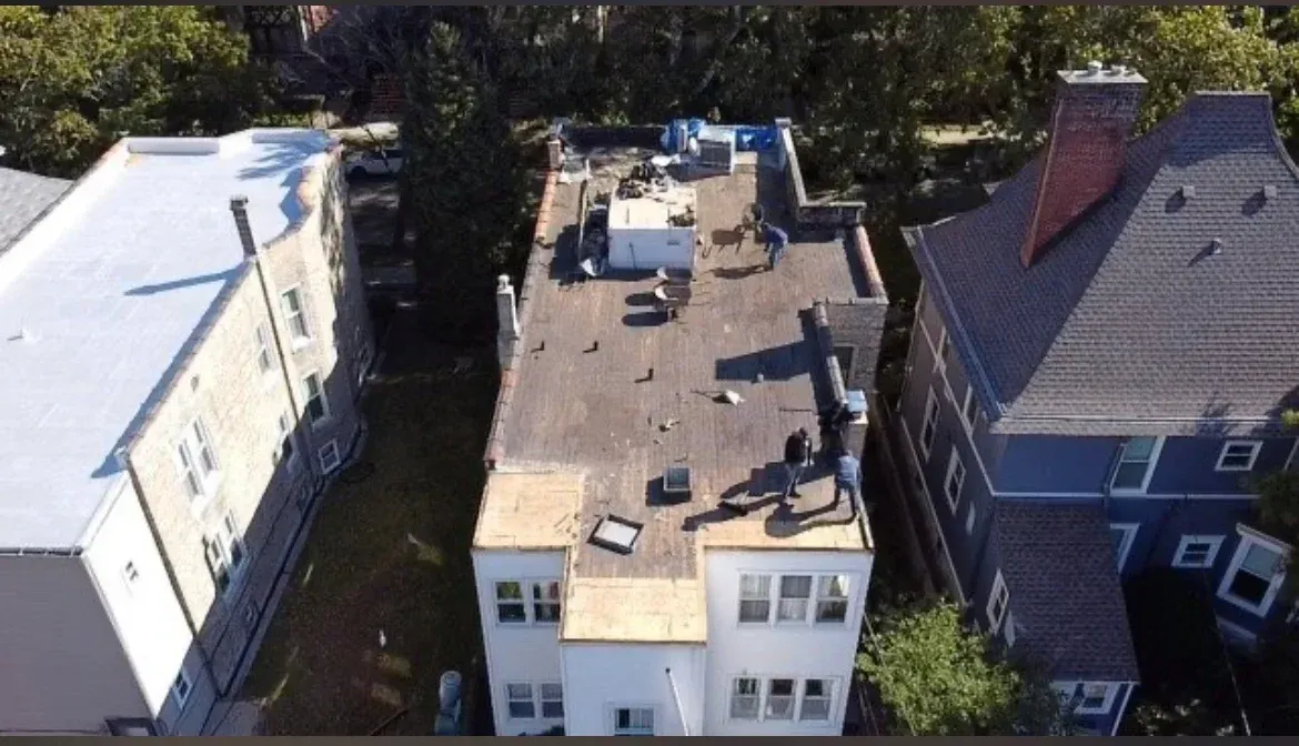 Aerial view of three adjacent residential buildings, with flat roofs and surrounding trees.