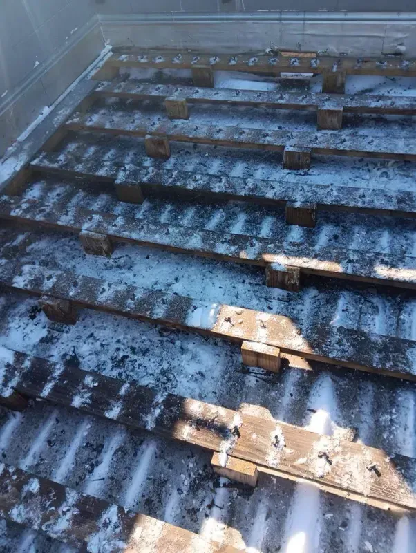 Rows of blue-gray roof panels with patches of snow and sunlight, viewed from above.