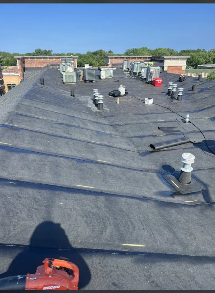 Flat black rooftop with HVAC units, vents, and a clear blue sky overhead