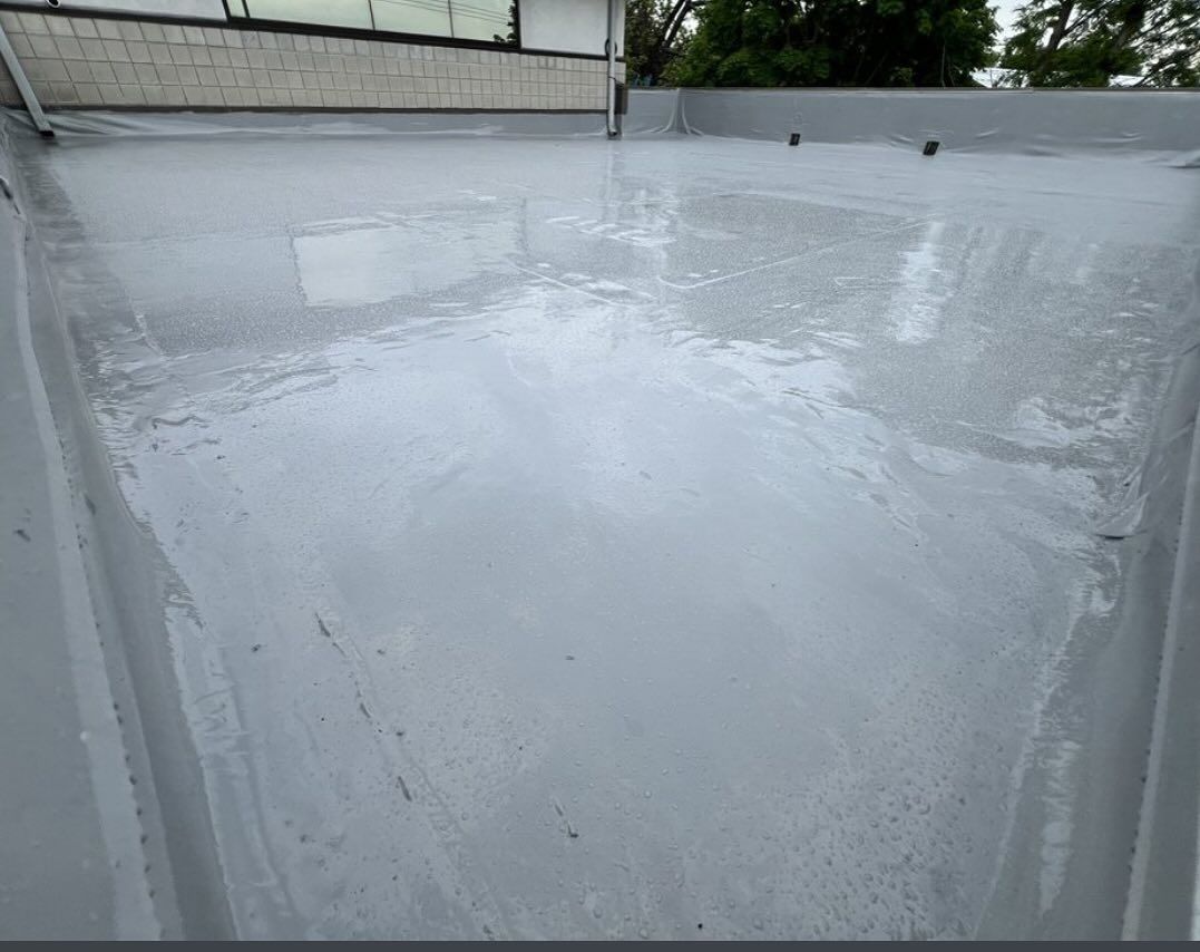 White, wet rooftop surface with a cloudy puddle reflecting the sky