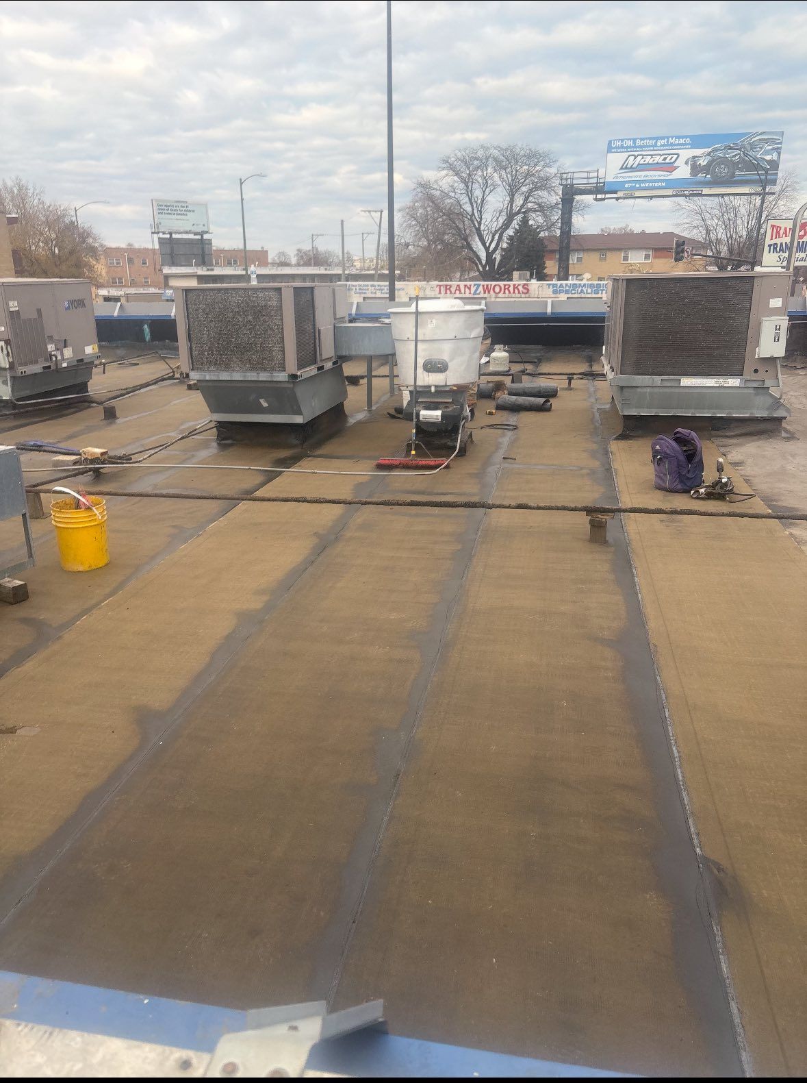 Rooftop with HVAC units, vents, and a cloudy sky in an industrial area