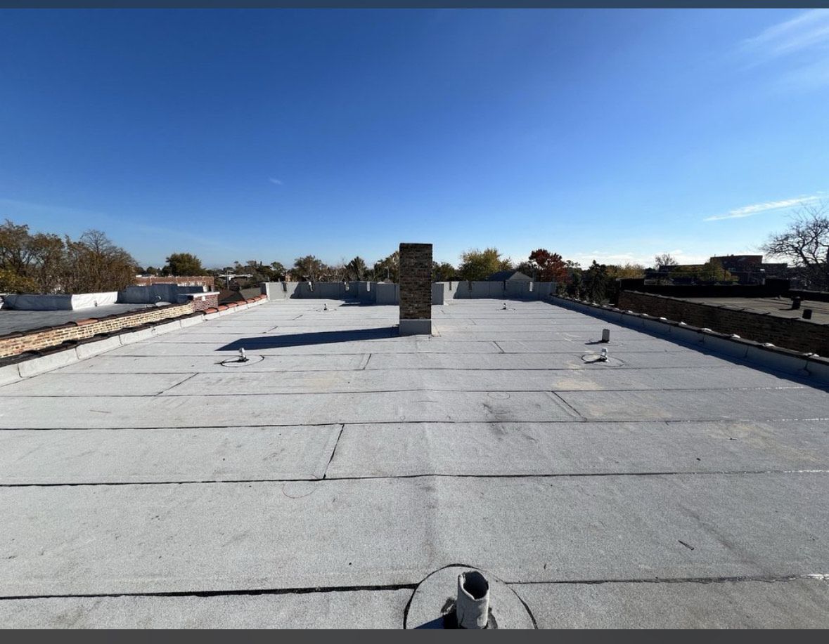 Flat white rooftop with a central vent under a clear blue sky.