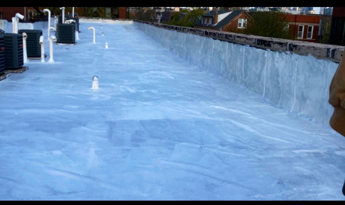 Frozen rooftop pool with blue ice and snow, lined by buildings and railings