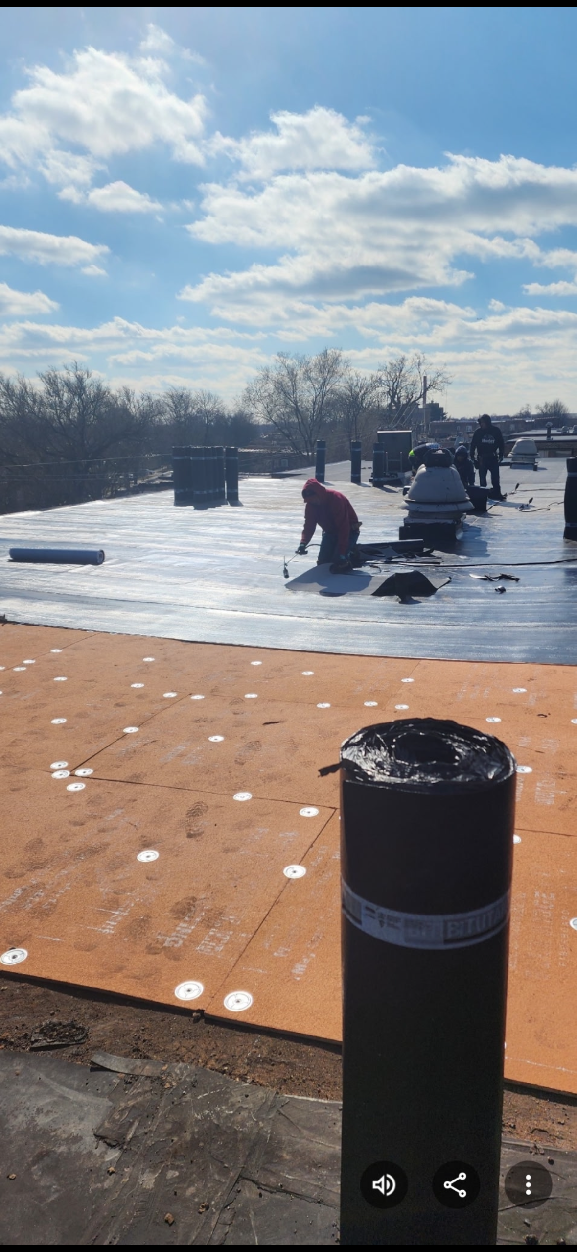 Snowy rooftop with people and patio furniture under a partly cloudy sky