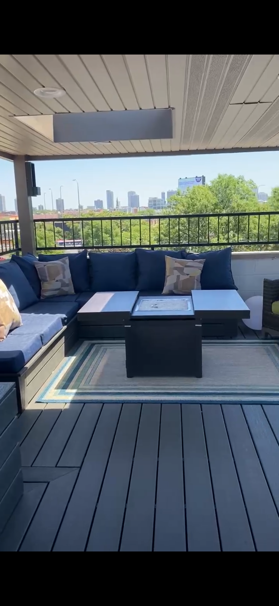 Rooftop patio with gray sectional sofa, coffee table, pergola, and city skyline view