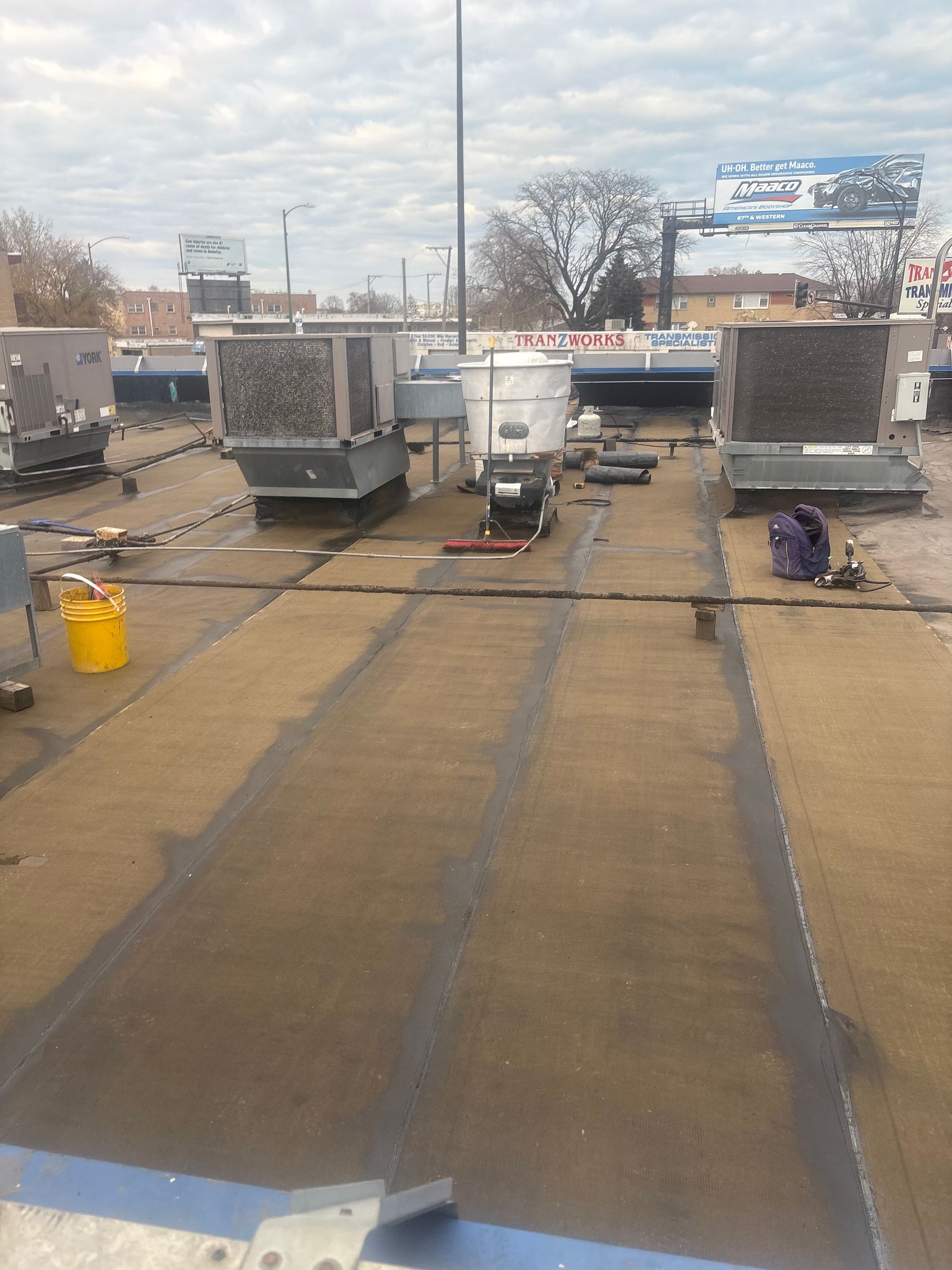Rooftop HVAC units and vents on a flat roof under a cloudy sky.