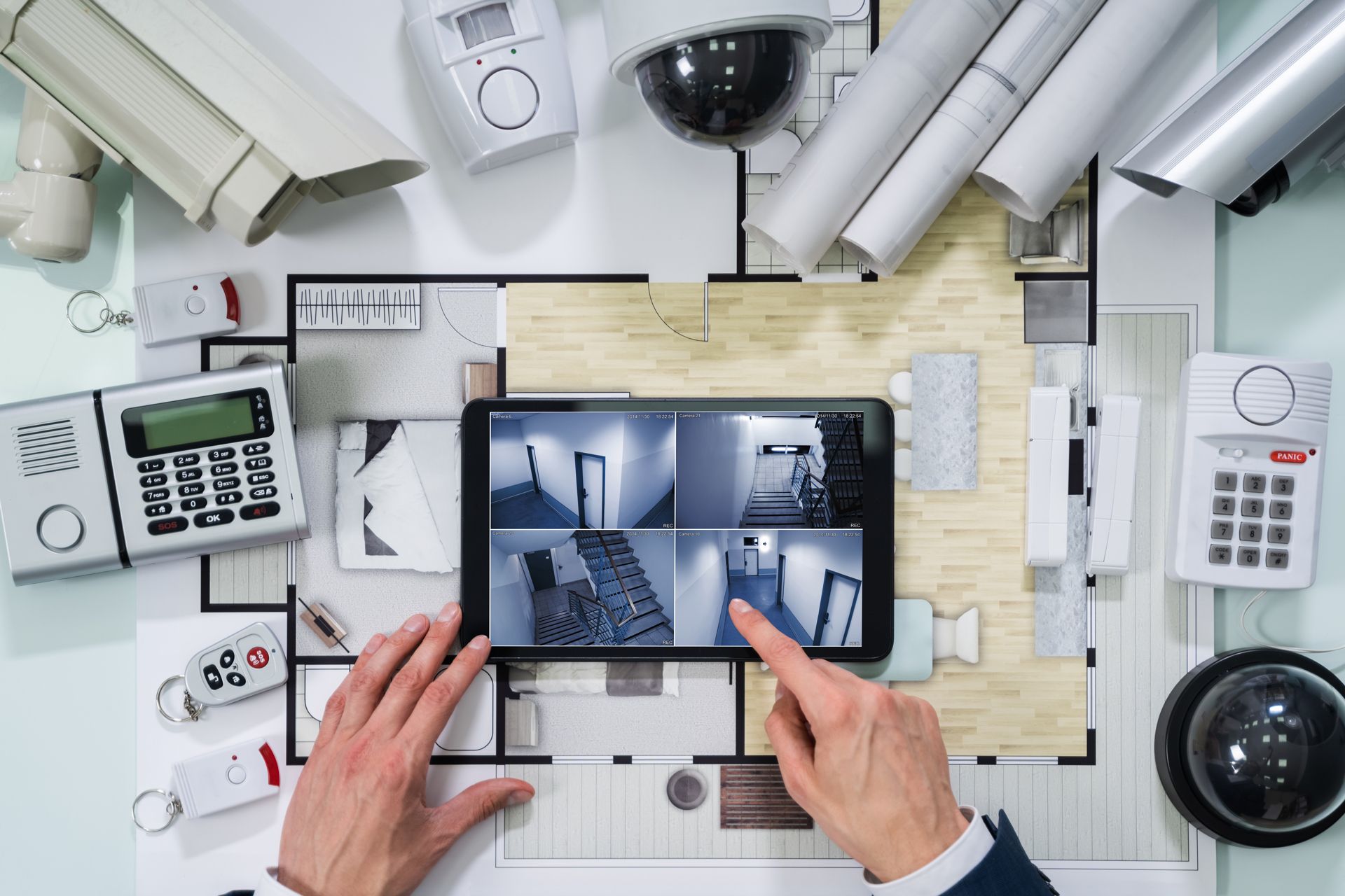 Hands pointing at a tablet displaying security camera