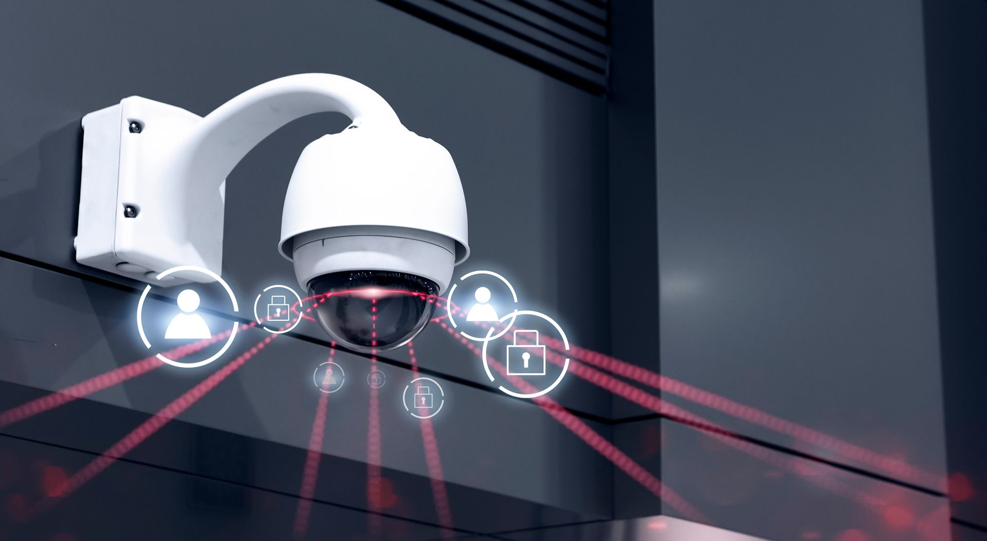 A white security camera mounted on a dark wall