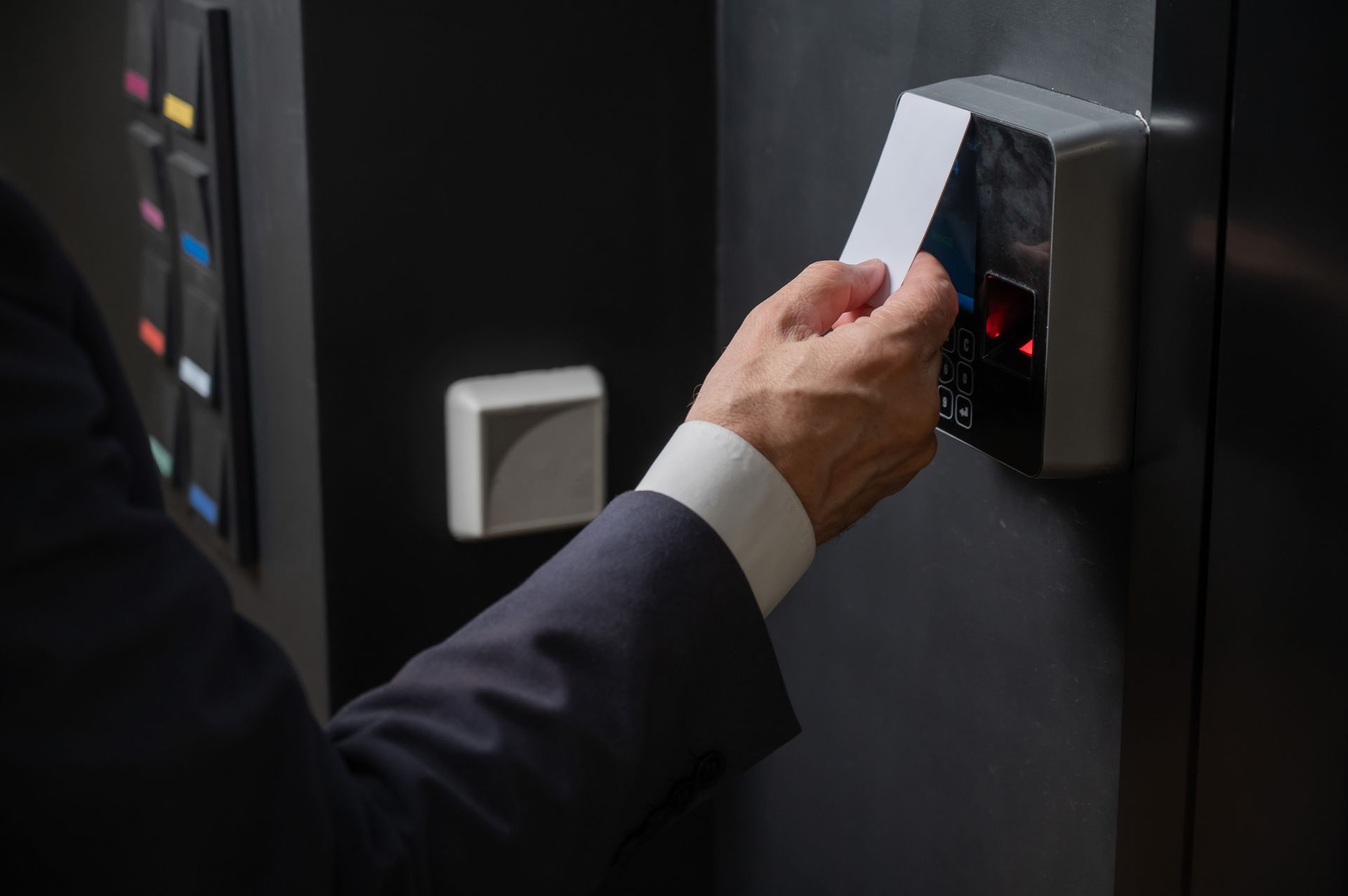 Person swipes access card at a reader mounted on a black panel