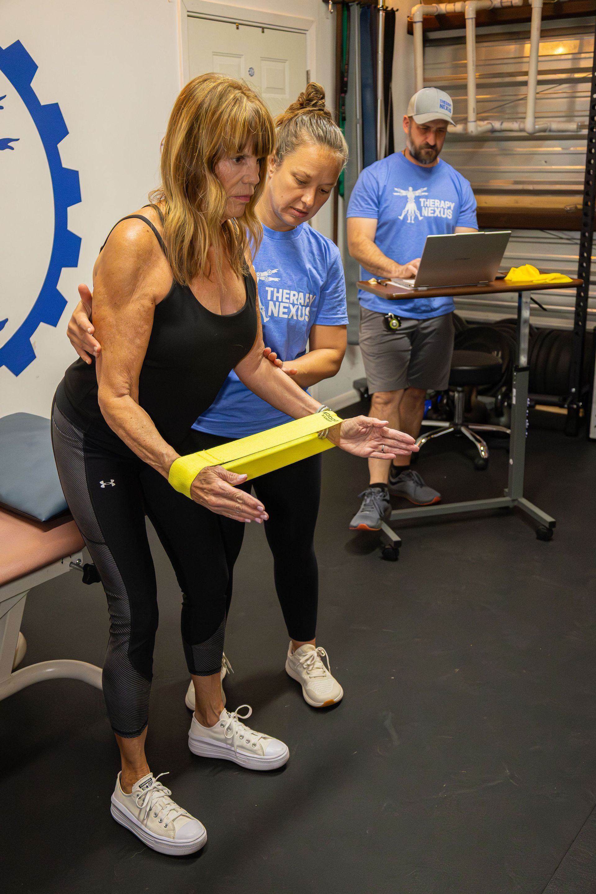 Woman doing physical therapy with band, therapist assisting.