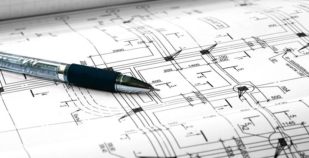 Bolígrafo negro sobre un plano arquitectónico con dibujos técnicos y medidas.