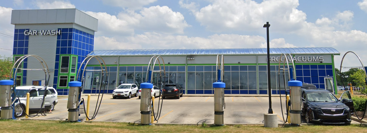Modern blue-and-green building with parked cars and a cloudy sky
