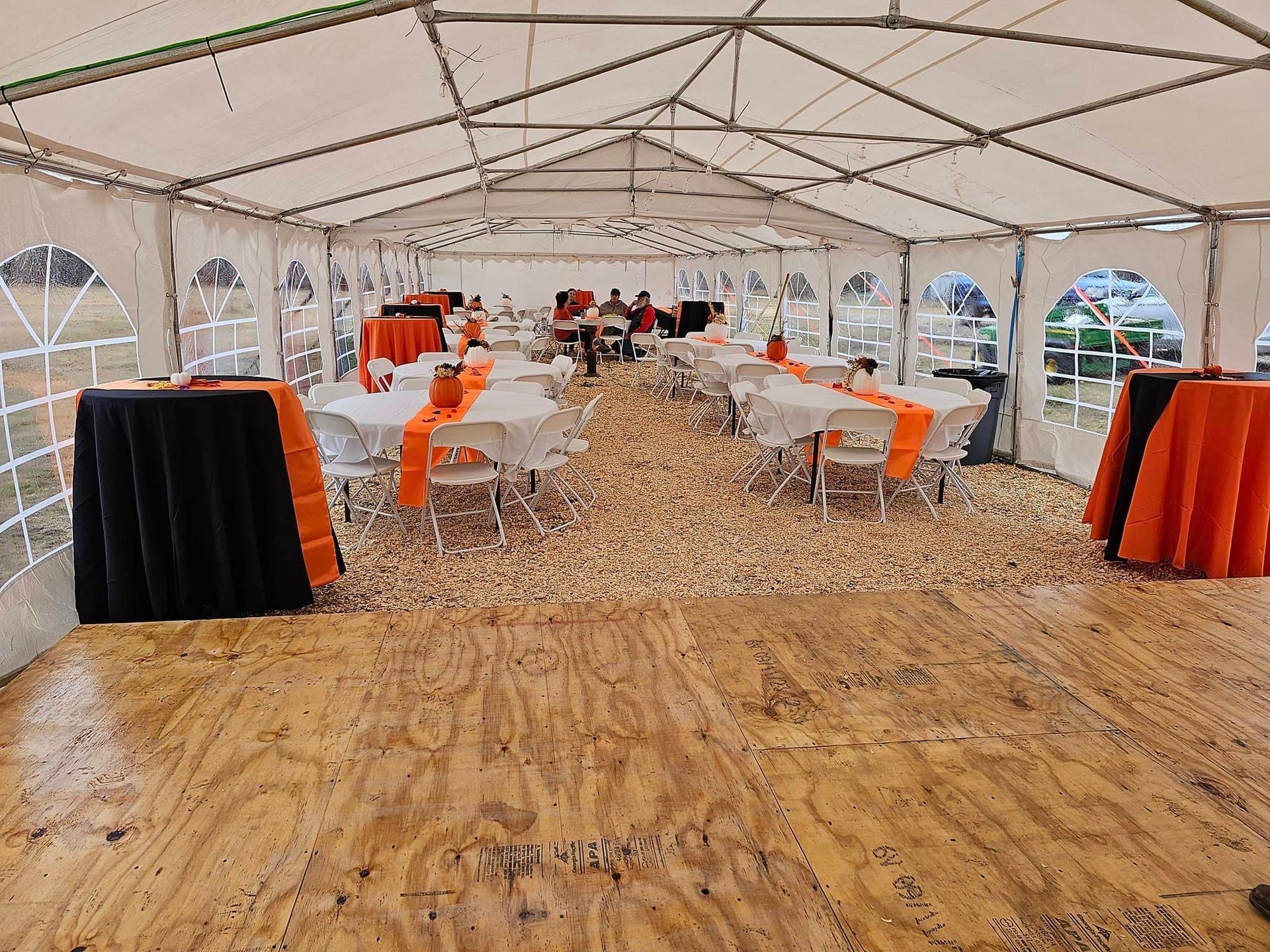 A large tent filled with tables and chairs and a wooden floor.
