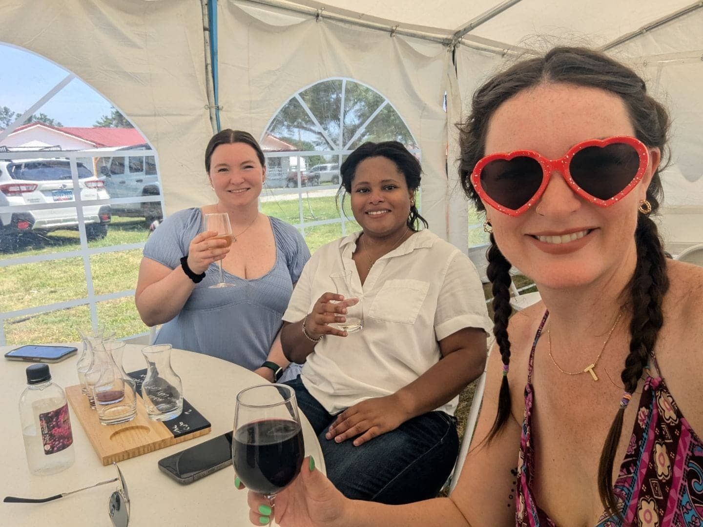 Three women are sitting at a table holding glasses of wine.