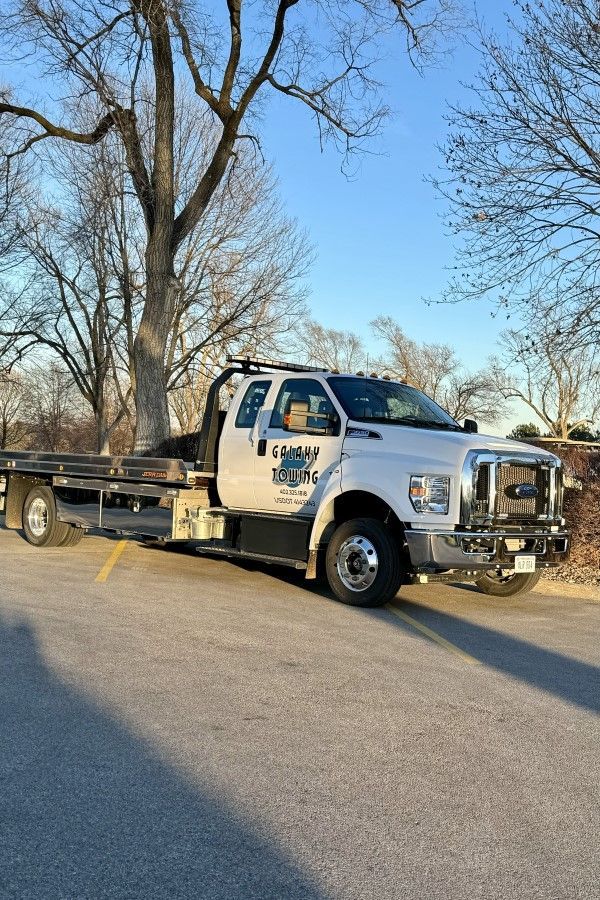 Tow truck parked on a tree-lined residential street in daylight