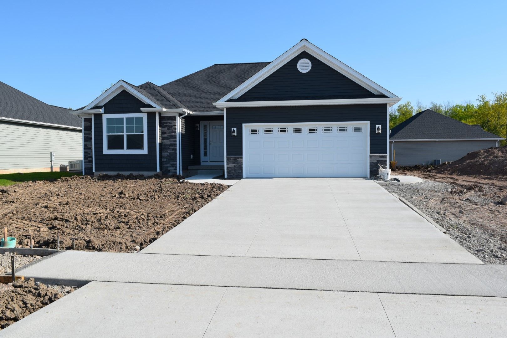 A black house with a white garage door and a concrete driveway